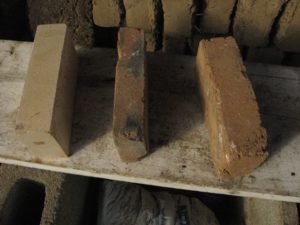 L to R: standard commercial hard firebrick, homemade brick of sand & soapstone dust, homemade brick of roadbase, sand, and dust. 